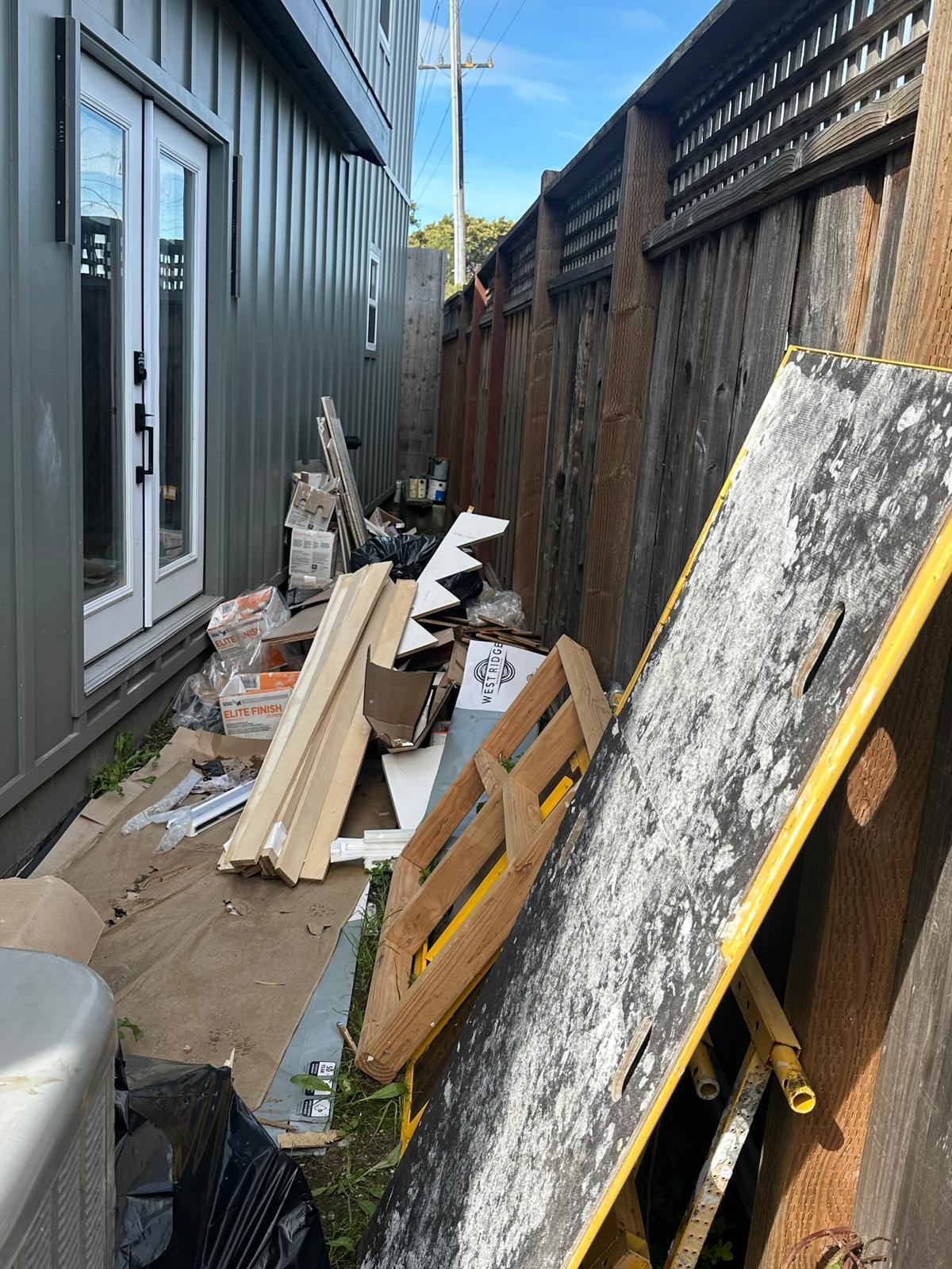 Building material scraps and clutter alongside a property
